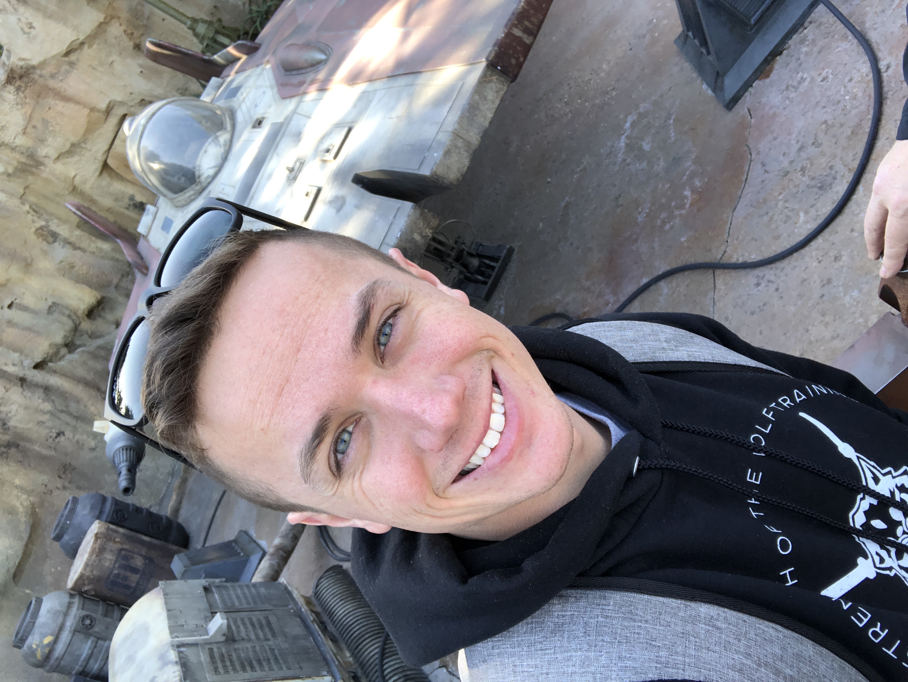 TJ smiling with sunglasses on his head and a black hoodie on, a Star Wars ship in the background.